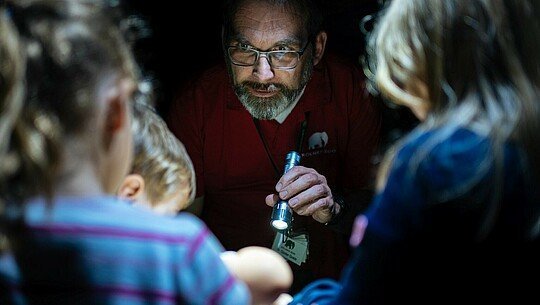 Zoobegleiter zeigt Kindern Insekten bei der Taschenlampenführung im Kölner Zoo