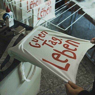 Dominik Siebel zeigt, wie im Modekollektiv eine Tasche mit der Sieb-druckmaschine bedruckt wird
