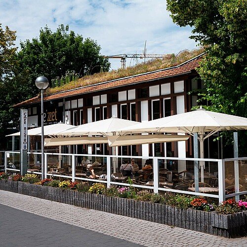 Blick auf das Café Le’zzet und seine begrünte Außenterrasse in Chorweiler