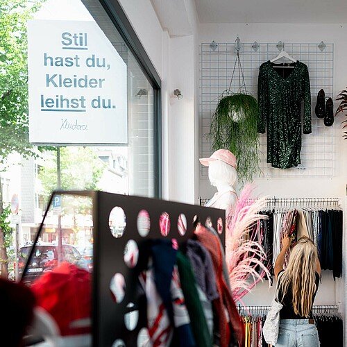 Im Verkaufsraum der Kleiderei in Ehrenfeld sucht eine Kundin nach einem passenden Kleidungsstück