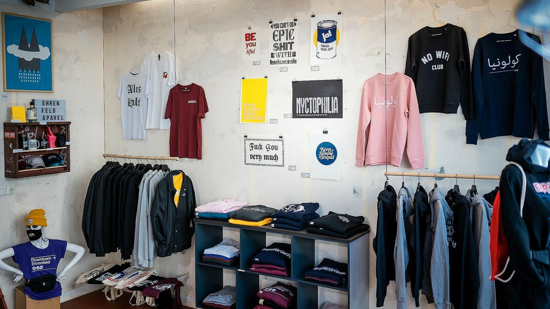 Kleidung mit Schriftzug in unterschiedlichen Sprachen im Laden „Ehrenfeld Apparel“ in Ehrenfeld