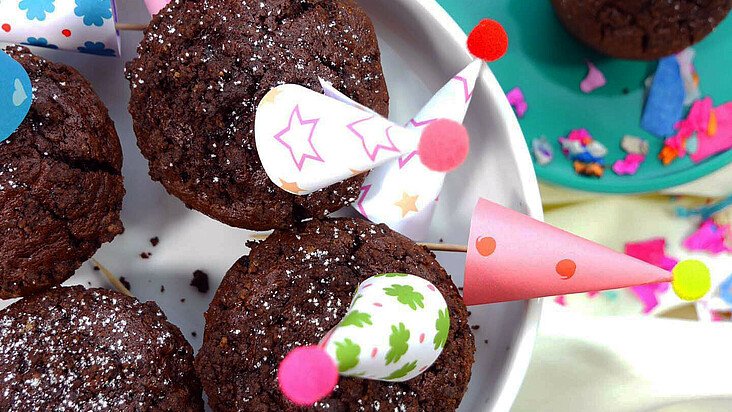 Schokoladen-Törtchen mit Knusperkonfetti auf bunten Tellern für die Karnevalsfeier