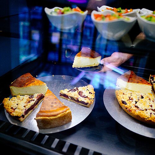 Teller mit Käsekuchen und Kirsch-Streuselkuchen in der Kuchentheke des Café Bachs in der Kölner Altstadt